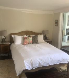 Una cama con sábanas blancas y almohadas en un dormitorio en Blythe Cottage en Long Melford