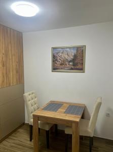 a dining room with a table and a painting on the wall at Apartman Eden in Brčko