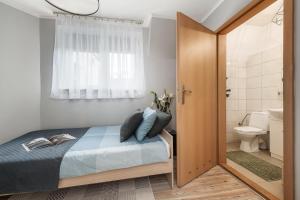 a bedroom with a bed and a bathroom with a toilet at Wielopole Homes by LoftAffair in Kraków