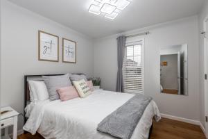 een witte slaapkamer met een groot bed met roze kussens bij Starved Rock & Ottawa Retreat Amazing Getaway Home in Ottawa