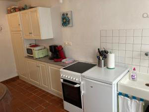 a kitchen with a white stove top oven next to a microwave at Gîte du Port in Châteauneuf-sur-Loire