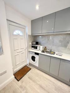 eine Küche mit einer Tür, einem Waschbecken und einer Mikrowelle in der Unterkunft 3 Cosy Homes Walking Distance to Mall with Parking Available to Book Separately 3 Bed House Or 1 Bed Apartment Or Studio in Golders Green