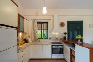 una cucina con mobili bianchi e un lavandino di Green House - Εξοχική κατοικία με μεγάλο κήπο a Nerotriviá Altre 24 foto