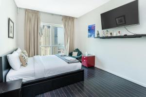 ein Hotelzimmer mit einem Bett und einem Flachbild-TV in der Unterkunft Minutes to Beach I Breath taking sea view in Dubai