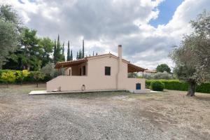 a small white house with trees and a yard at Green House - Εξοχική κατοικία με μεγάλο κήπο in Nerotriviá