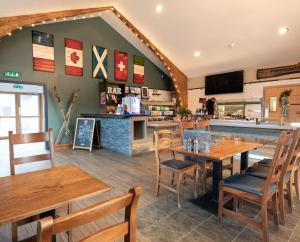 a restaurant with wooden tables and chairs and a counter at The Base Camp Hotel, Nevis Range in Fort William
