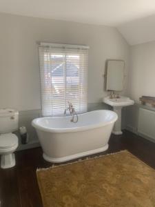 Blythe Cottage في لونغ ميلفورد: حوض استحمام أبيض في حمام مع مرحاض