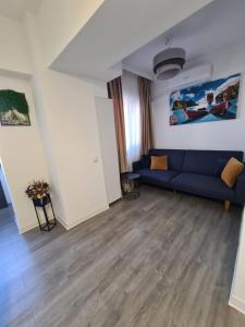 een woonkamer met een blauwe bank en houten vloeren bij Central Apartment in Târgu Jiu