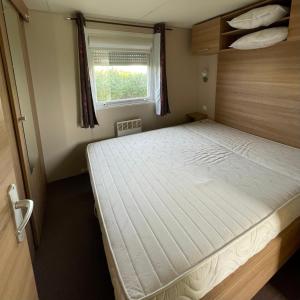 łóżko w małym pokoju z oknem w obiekcie Parc Résidentiel La Listra - Bungalow w mieście Belgodère