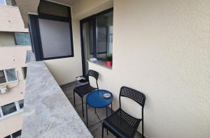 een balkon met 2 stoelen, een tafel en een raam bij Central Apartment in Târgu Jiu