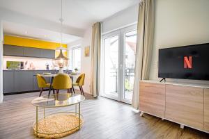 uma sala de estar com uma televisão, uma mesa e cadeiras em HOMEFY - Come Together Apartment em Essen