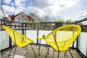 2 chaises jaunes et une table sur un balcon dans l'établissement Homefy Come-Together Apartment - Balkon - Aufzug - Free Parking - Smart TVs, à Essen