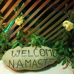 una señal que dice namaste de bienvenida junto a una planta en Shiva's Hippies Colony en Sauraha