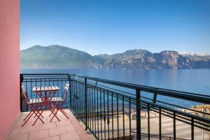 a table and chair on a balcony with a view of the water at Casa Rosa in Brenzone sul Garda