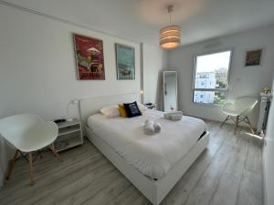a white bedroom with a bed and two chairs at Les Terrasses Marines - Vue imprenable sur le port de plaisance in Vannes