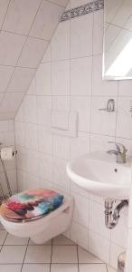 Baño blanco con lavabo y aseo en Restaurant und Pension Zur Nassen Ecke, en Wittenbeck