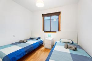 2 Betten in einem weißen Zimmer mit Fenster in der Unterkunft Apartamento Tazacorte in Tazacorte
