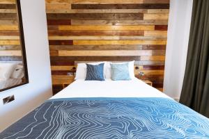 a bedroom with a wooden accent wall and a bed at The Base Camp Hotel, Nevis Range in Fort William