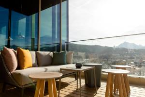 a living room with a couch and tables in front of a window at Motel One Innsbruck in Innsbruck