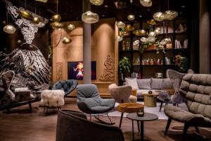 a lobby with chairs and tables and a room with akritisks at Motel One Innsbruck in Innsbruck