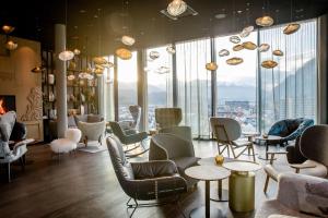 a room with chairs and tables and large windows at Motel One Innsbruck in Innsbruck