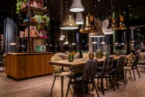 a dining room with a table and chairs and pendant lights at Motel One Innsbruck in Innsbruck