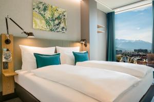 two beds in a hotel room with a window at Motel One Innsbruck in Innsbruck