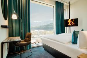 a hotel room with a bed and a large window at Motel One Innsbruck in Innsbruck