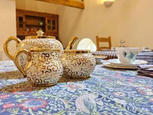 dois bules de chá e uma chávena sobre uma mesa em Henllys Estate B and B em Llandovery