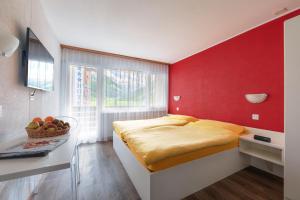 a bedroom with a bed and a red wall at Hotel Mountime in Täsch