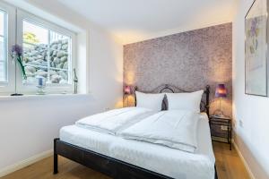 a bedroom with a bed with white sheets and a window at Ferienwohnung Wattn Blick - urlauben mit Wattblick in Munkmarsch Sylt in Munkmarsch