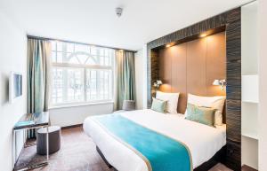 um quarto de hotel com uma cama grande e uma janela em Motel One Edinburgh-Princes em Edimburgo
