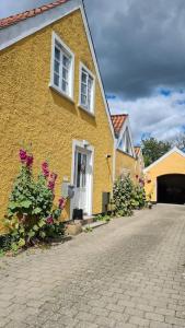 a yellow house with flowers in front of it at Sydfynsk idyl tæt på det hele. in Svendborg