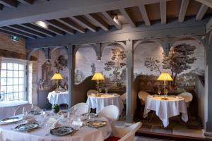 jadalnia ze stołami i krzesłami oraz malowidłem ściennym w obiekcie Le Vieux Logis w mieście Trémolat