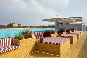 a deck with benches and umbrellas and a pool at The Social Hub Toulouse in Toulouse