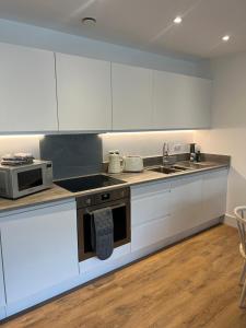 cocina con armarios blancos y microondas en 45 Teesra House, en Plymouth