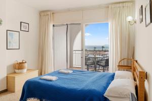 1 dormitorio con cama azul y balcón en Estudio Welcs EMP - 044 - frente al mar, en Empuriabrava