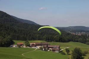 巴特維塞的住宿－Gästehaus Kleinbuch，绿色降落伞飞过田野中的房屋