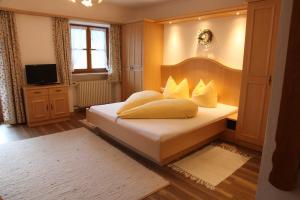 Un dormitorio con una cama con almohadas amarillas. en Gästehaus Kleinbuch en Bad Wiessee