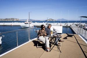 mężczyzna i kobieta siedzący na pokładzie łodzi w obiekcie ALMALO Floating House - Casa Galleggiante w mieście Procida