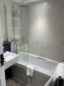 baño blanco con ducha y lavamanos en Cottesmore Hotel Golf & Country Club, en Crawley