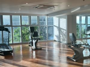 a gym with treadmills and exercise equipment in a room with windows at Uptown Parksuites II in Manila