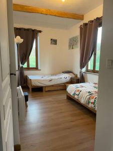 a bedroom with two beds and two windows at Maisonnette de campagne 70m2 in Lartigue