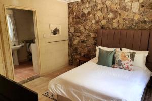 a bedroom with a bed and a stone wall at Beautiful 1-Bed Cottage in Juliasdale in Juliasdale