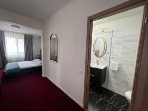 um quarto de hotel com casa de banho com cama e espelho em Eden Boutique Accommodation em Bucareste