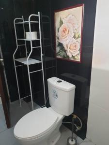 łazienka z toaletą i zdjęciem kwiatów w obiekcie Stargazers Apartment w mieście Olongapo