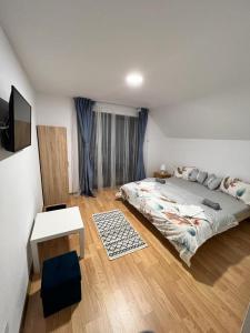 Schlafzimmer mit einem Bett, einem Tisch und einem TV in der Unterkunft Pensiunea RNB Maramures in Şurdeşti