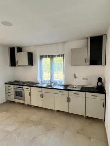 a kitchen with white cabinets and black counter tops at Pensiunea RNB Maramures in Şurdeşti
