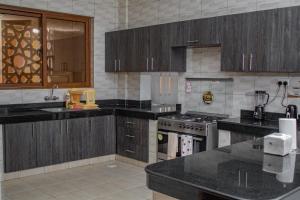eine Küche mit Holzschränken und schwarzen Arbeitsplatten in der Unterkunft Destiny properties in Mombasa