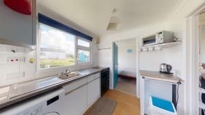 eine Küche mit einem Waschbecken und einem Fenster in der Unterkunft F38 Barton, Riviere Towans in Hayle